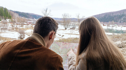 A young couple studies the local roadmap while discussing the further route of their road trip. High quality photo. Rear view - Powered by Adobe