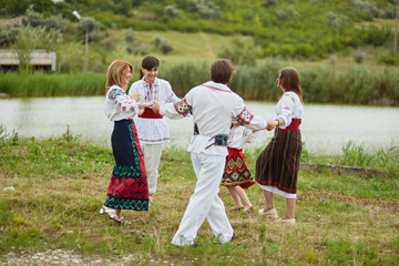 Happy family with kids in traditional romanian dress in a countryside, park. Father, mother, son...