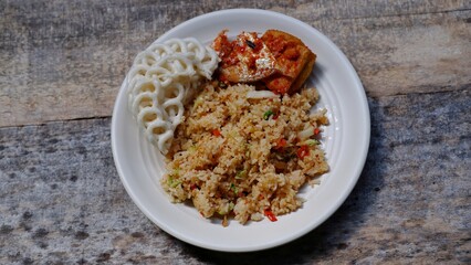 Indonesian style fried rice known as Nasi goreng, served with crackers on wooden background 
