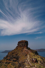 Portrait image of the top of Skaros rock in Santorini. Beautiful and interesting swirl of cloud formation about the natural rock formation.
