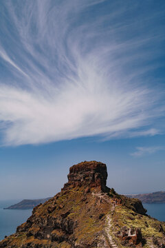 Portrait image of the top of Skaros rock in Santorini. Beautiful and interesting swirl of cloud formation about the natural rock formation.
