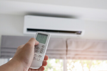 Hand with remote control directed on air conditioner