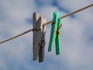 drei Klammern aus Holz und Plastik an einer Wäscheleine vor blauem Himmel