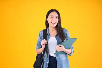 Portrait Cheerful young asian female student with backpack holding books education back to school and lifestyle concept yellow background.