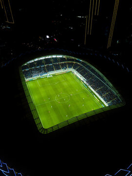 Batumi, Georgia - May 8 2022: Picture from a drone of the new stadium in Batumi. Night view from a drone on a football field with players during a match. Vertical photo