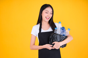 attractive asian female smile wearing  apron pointing fingers to plastic bottle in a garbage bag for Recycling, world environment day.