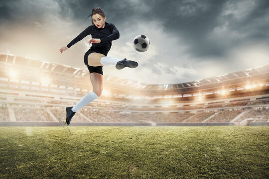 Young female soccer or football players in sportwear kicking ball for the goal in action at the stadium. Concept of healthy lifestyle, sport, motion, movement.