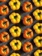 Pattern of yellow and orange sweet bell pepper on black concrete background. Creative flatlay with spring vegetables.