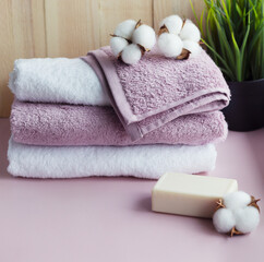 Obraz na płótnie Canvas Set of towels with piece of soap and flowers of cotton