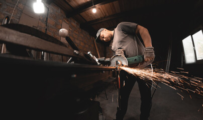 A man works with an angle grinder in his home workshop. Making metal products with your own hands