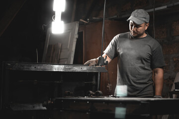 A worker prepares a woodworking machine for work in his home workshop. Making metal products with your own hands