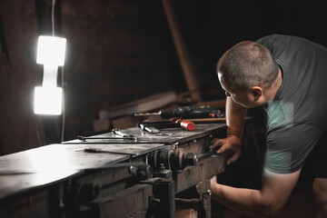 A worker prepares a woodworking machine for work in his home workshop. Making metal products with your own hands