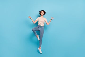 Fototapeta na wymiar Full length photo of dreamy cute woman wear beige t-shirt jumping high practicing yoga isolated blue color background