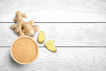 Fresh Ginger root and ginger powder in wooden bowl isolated on white wood table background. Top view. Flat lay. Copy space.