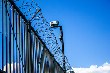 Fototapeta premium Barbed wire on a high fence against the sky. Barbed wire on the border of the country. Security of the border area.