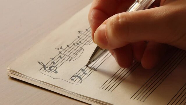 Handwritten notes and female hand holding a pen and writing notes, composing music, selective focus
