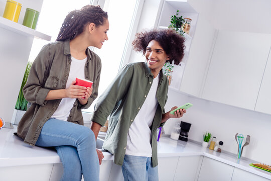 Photo of good mood siblings spend time together in kitchen enjoy morning coffee have conversation with each other