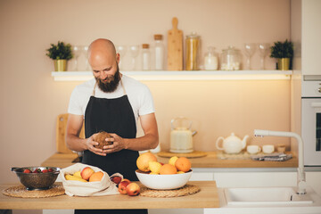 Millennial man preparing ingridients for making smoothies at the kitchen.