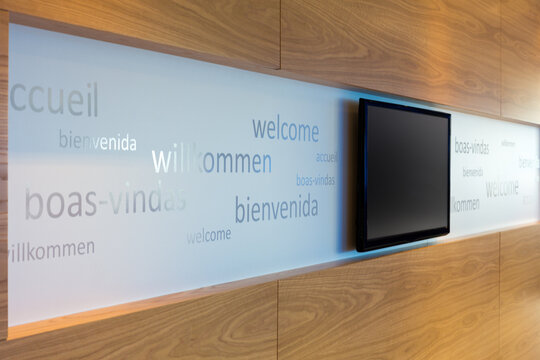 A welcoming office foyer with signage in multiple languages with flat screen TV