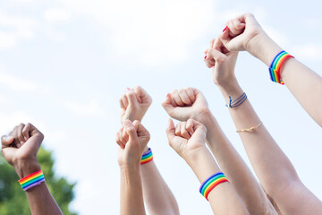 Closed hands claiming gay pride rights with gay pride bracelet outdoors