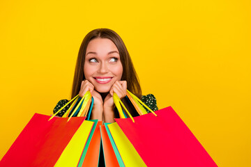 Photo of pretty positive girl hands hold packages toothy smile look empty space isolated on yellow...