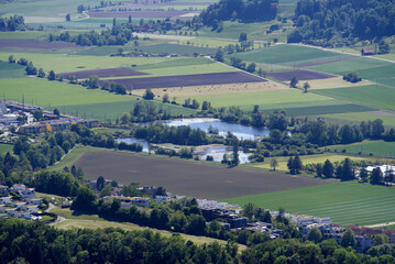 Fototapeta na wymiar Aerial view of midland with agricultural fields, wood, ponds and hills seen from local mountain Uetliberg on a sunny spring day. Photo taken May 18th, 2022, Zurich, Switzerland.