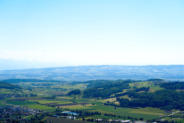 Fototapeta na wymiar Aerial view of midland with agricultural fields, wood and hills seen from local mountain Uetliberg on a sunny spring day. Photo taken May 18th, 2022, Zurich, Switzerland.