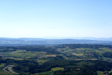 Aerial view of midland with agricultural fields, wood and hills seen from local mountain Uetliberg on a sunny spring day. Photo taken May 18th, 2022, Zurich, Switzerland.