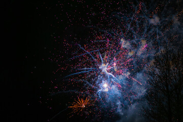 Fading sparks of fireworks in red and yellow, against the background of the night sky
