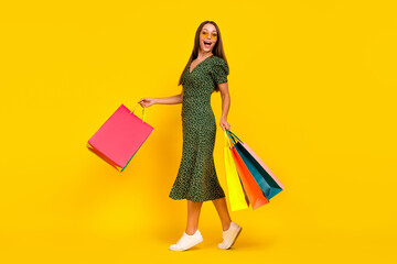 Full length photo of overjoyed pretty person arms hold packages isolated on yellow color background