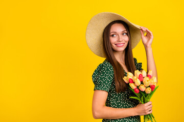 Profile photo of cute stunning lady touch sunhat hold flowers look empty space toothy smile isolated on yellow color background