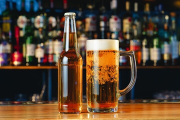 Beer glass and bottle on wooden countertop in a pub