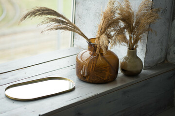 two glass vases are on the windowsill