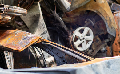 Fototapeta premium Broken and burned cars in the parking lot, accident or deliberate vandalism. Burnt car. Consequences of a car accident. Damaged by arson. Dump of civilian vehicles shot by Russian troops in Ukraine.