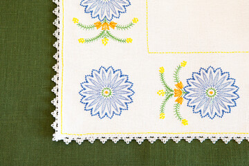 Detail of embroidery on a tablecloth in the form of blue cornflowers, on a green textural...