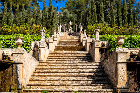 An aged Staircase called Apollo Staircase lined with stone sculptures between lemon trees, cypresses and ivy leads to a monument of the god Apollo in Apollo garden of the famous Raixa public estate.