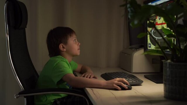 Cute caucasian boy playing video game at desktop computer at home