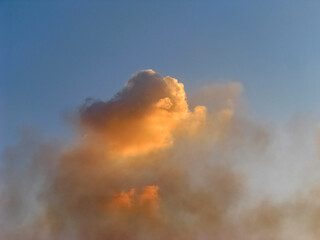 The Setting Sun Colored a Cumulus Cloud High in The Blue Sky Orange