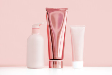 Mock up pink cosmetic bottle and tubes. Minimal monochrome composition of skin care products.
