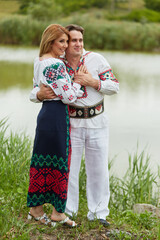 Couple image of a smiling wife and husband together embracing posing in Romanian national clothes.