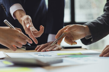 A group of people pointing to papers on a table in a conference room, a financial analyst attending a company audit meeting with the finance and accounting department. Meeting concept.