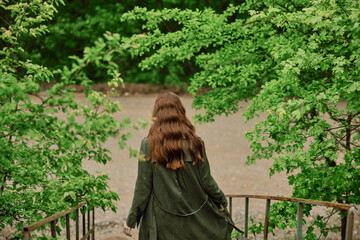 a woman with beautiful, long, red hair descends to a mountain river after rain
