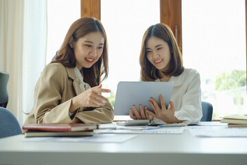 Negotiation, Analysis, Discussion, Portrait of an Asian women economist and marketer using tablet computer to plan investments and financial to prevent risks and losses for the company