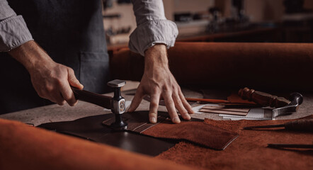 Tailor processing hammers seam on leather goods, Handmade craftsman - obrazy, fototapety, plakaty