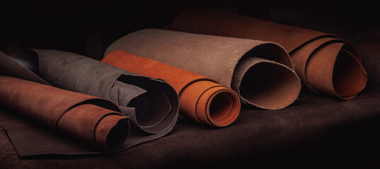 Different rolls of multi-colored natural color leather on rack in workshop. Banner Materials for...
