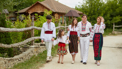 Full length image Happy family with kids in traditional romanian clothes in a countryside. Father, mother, son and daughters walking outside.