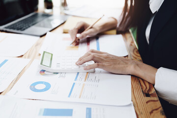 financial, Planning, Marketing and Accounting, Asian woman Economist using calculator to calculate investment documents with partners on profit taking to compete with other companies