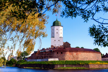 Medieval fortress in Vyborg. Castle on the water against the background of a blue sky with foliage