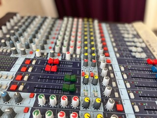 Fototapeta premium Rows of buttons, tumblers, switches, knobs and sliders on the professional audio mixer (dj console). Audio equipment in the studio. Sound board for mixing, recording and editing