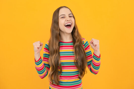 Teenager child overjoyed successful do winner gesture clench fist say yes isolated on yellow background studio. Excited face, cheerful emotions of teenager girl.